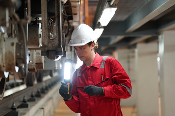 Professional technician worker hold light tube to check and maintenance part of train in electrical or metro train factory.