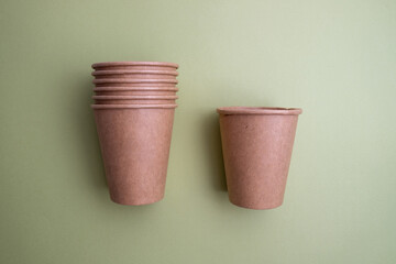 Top view of brown kraft paper cups, straws on a colored background. Recyclable street food packaging. Zero waste. Paper dishes. Disposable takeaway cup