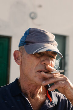 Close-up portrait features an elderly man confidently smoking a cigar