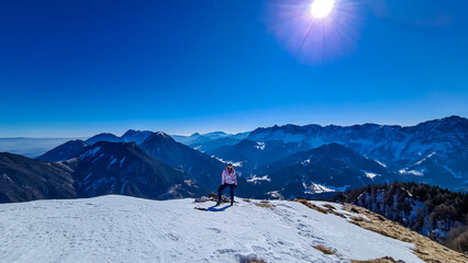 Woman on panoramic hiking trail on way to snow covered mountain peak Ferlacher Horn in Carinthia,...