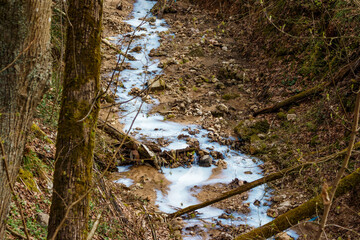 A stream in a ravine of white and blue color, environmental pollution by enterprises, drainage of...