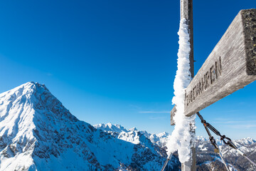 Scenic view of frozen summit cross Ferlacher Spitze in Karawanks, Carinthia, Austria. Clear blue sky in winter wonderland in remote Austrian Alps. Looking at snow capped mountain Mittagskogel (Kepa) - Powered by Adobe