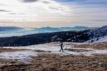 Woman with backpack hiking in cold windy winter at Ladinger Spitz in the Saualpe mountain range,...
