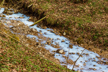 A stream in a ravine of white and blue color, environmental pollution by enterprises, drainage of construction fluid