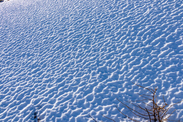 Snow covered alpine meadow in the Lavanttal Alps in Carinthia, Austria. The snow has small, irregular patterns that resemble the texture of the ground. Terrain formed by wind. Natural pattern - obrazy, fototapety, plakaty