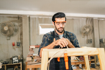 Carpenter working with electric planer on wooden plank in workshop. Craftsman makes own successful...