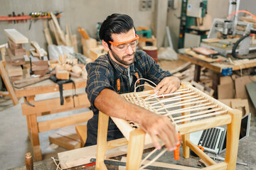 Diligently skilled man work with wood in carpenter's shop, using tools and equipment to transform...