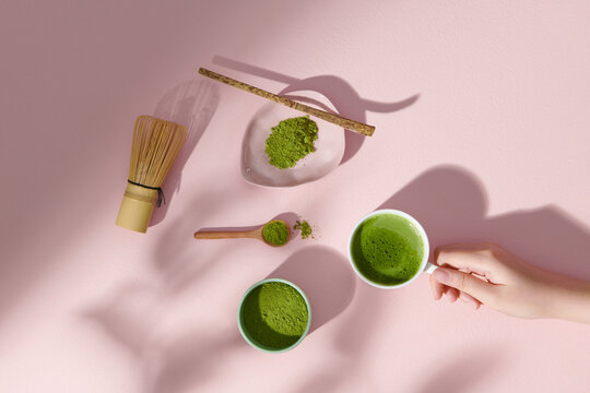 Bowl of fresh matcha tea, bamboo whisk and powder on light table
