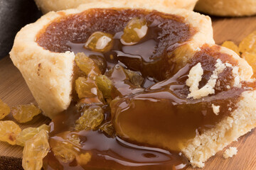 a butter tart on a wooden board showing the sweet filling and raisins flowing onto the board