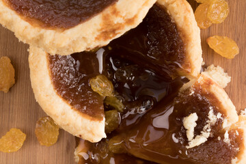 a butter tart with one piece cut out showing the soft filling and raisins on a wooden board

