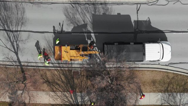 Aerial shot of Tree cutting services worker loading cut tree branches into the wood chipper machine for shredding