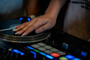 DJ with acrylic nails spins beats on an electronic sound mixing table