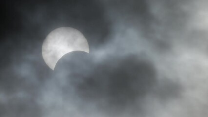 Full solar eclipse happening in real time afternoon at April 8 2024 in Ontario Canada. Moon makes shadow on Earth's surface by blocking sun's light. Solar Eclipse totality moment in the dark clouds.