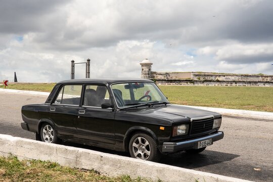 Black Lada Riva 2107 (VAZ 1600) saloon car in Havana, Cuba in front of Morro Castle