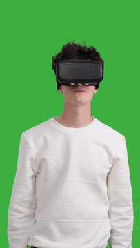 Happy and joyful Caucasian young man using VR headset on chroma key background. Innovation technology, futuristic entertainment. Vertical video.