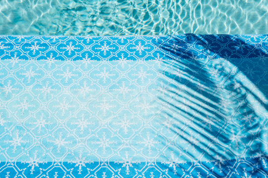 Palm leaf shadow poolside with towel