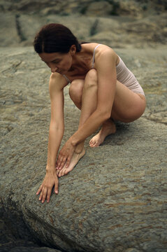 a fit woman touches a stone in nature