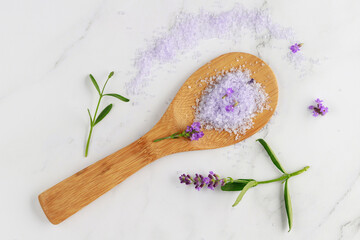 Lavender violet salt on wooden spoon and  fresh flowers on white marble background.