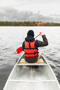 Young man rowing a kayak on a forest Lake