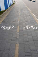 A two-lane bicycle path with painted signs and markings paved with road tiles