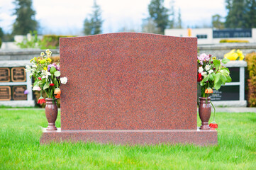 Large blank tombstone with flowers in cemetery