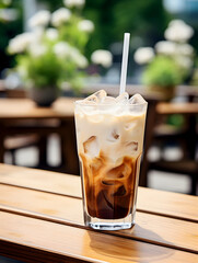 A glass of iced coffee with milk on wooden cafe table outdoors 