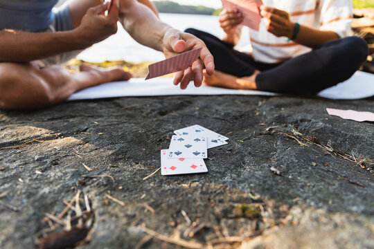 Cheerful friends playing cards in hiking trip during sunset