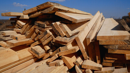 Many wooden planks lie on the ground in the open air. Building materials for the construction of the future house.