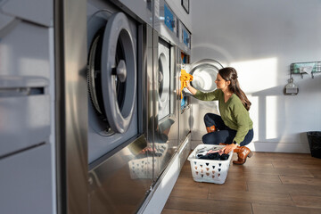 Woman doing laundry in the laundromat shop