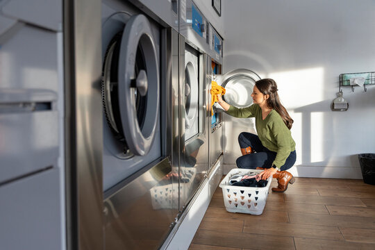 Woman doing laundry in the laundromat shop