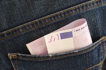 A close-up shot of  a five hundred euro banknote in the back pocket of blue jeans.