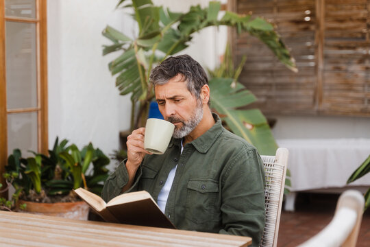 Man Reading A Book Sitting On The Terrace