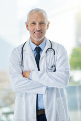 Doctor, confidence and portrait of mature man in a hospital at a cancer research clinic with arms crossed. Professional, medical employee and uniform with healthcare, wellness and health consultant