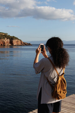 young woman taking photos at sunset