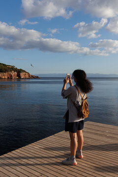 young woman taking photos at sunset