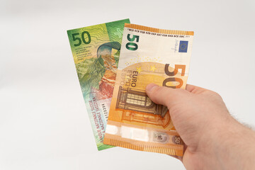 Man holding 50 CHF Swiss franc and 50 EUR Euro banknote paper currency isolated on white background