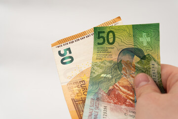 Man holding 50 CHF Swiss franc and 50 EUR Euro banknote paper currency isolated on white background