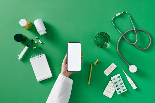 Workplace of a doctor with blank mobile screen in hand