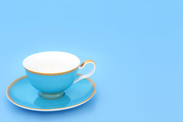 Blue and gold bone china tea cup. Elegant luxury drinking set on pastel blue background with copy...