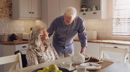 Elderly, married couple and smile in kitchen for breakfast, morning or relax for retirement, love or support. Pensioners, talking and home for cake for relationship, joy and trust for happiness