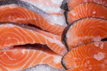 A close up of a variety of fish fillets, including salmon, with ice on top. Concept of freshness and abundance
