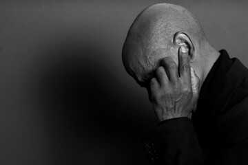 deaf man suffering from deafness and hearing loss on grey black background with people stock image...