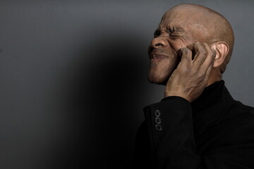 deaf man suffering from deafness and hearing loss on grey black background with people stock image...