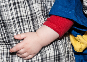 Different fabric clothing close-up with child’s hand