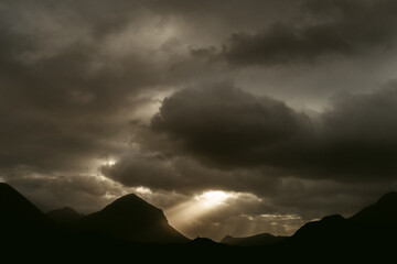Cloudy sunset sky over dark mountains range
