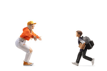 Full length profile shot of a schoolboy running to hug a young female