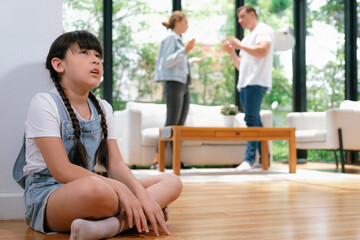 Stressed and unhappy young girl huddle in corner crying and sad while her parent arguing in...