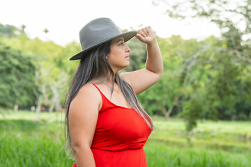 latina woman looking towards the horizon while clutching the gray hat on her head with her hand