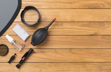 Different camera cleaning tools on wooden background, top view