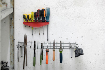 Screwdrivers and other tools hanging on a wall in a workshop